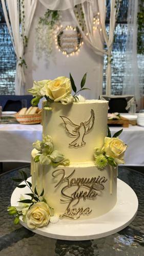 a white wedding cake with yellow roses on a table at Kaszubskie Wzgórze - Całoroczne Domki Drewniane in Perlino
