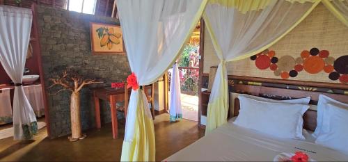 a bedroom with a bed with white drapes at KINTANA LODGE in Ile aux Nattes