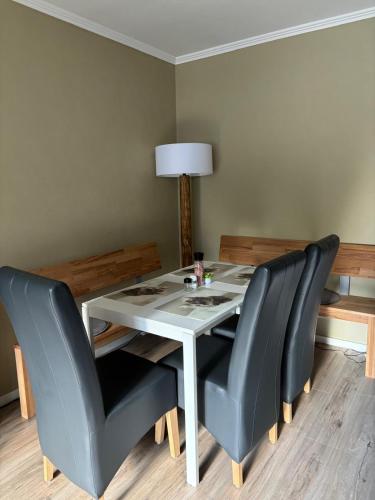 a dining room table with two black chairs and a white table at Haus Nina near Willingen and Winterberg in Olsberg