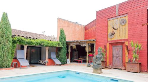 a red building with a swimming pool in front of it at Couleurs du Sud in Vallon-Pont-dʼArc