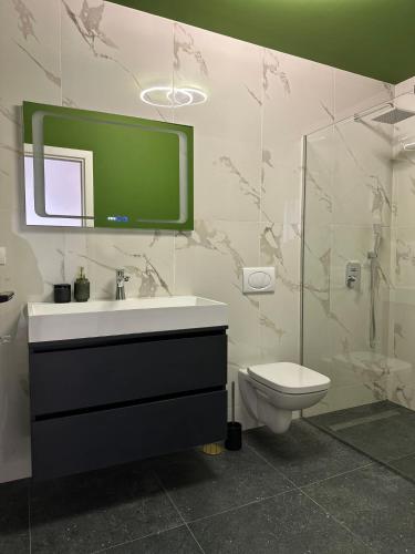a bathroom with a sink and a toilet and a tv on the wall at Grey Residence in Drobeta-Turnu Severin