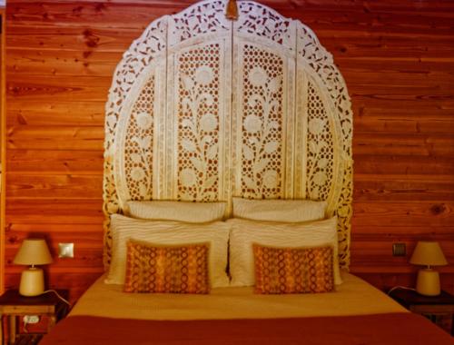 a bed with a white headboard in a room at Couleurs du Sud in Vallon-Pont-dʼArc