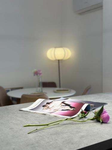 a table with a book and flowers on it at Grey Residence in Drobeta-Turnu Severin