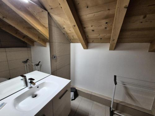 La salle de bains est pourvue d'un lavabo blanc et de plafonds en bois. dans l'établissement La Residence - Appartement La Résidence MAE-9411, à Vénosc