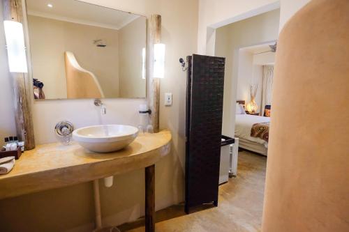 a bathroom with a sink and a mirror and a bed at Afrikhaya Guest House in St Lucia