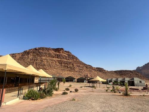 a building with umbrellas in front of a mountain at Dream Bedouin Life Camp Wadi Rum in Disah