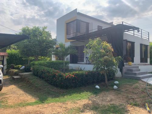a white house with a tree and bushes at Melgar Alojamiento Villa Claudia in Melgar