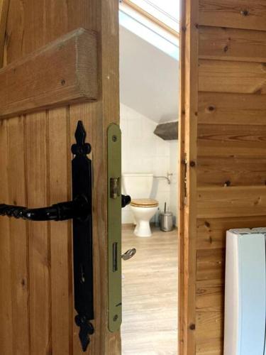 une porte donnant sur une salle de bain avec toilettes dans une pièce dans l'établissement Maison Au bois du Haut Folin, à Saint-Prix