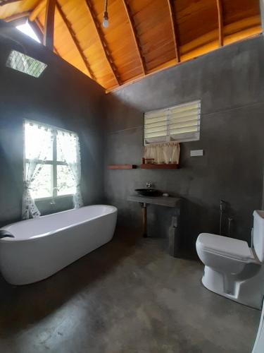 a bathroom with a white tub and a toilet at Dins Nature Villa in Elgiriya