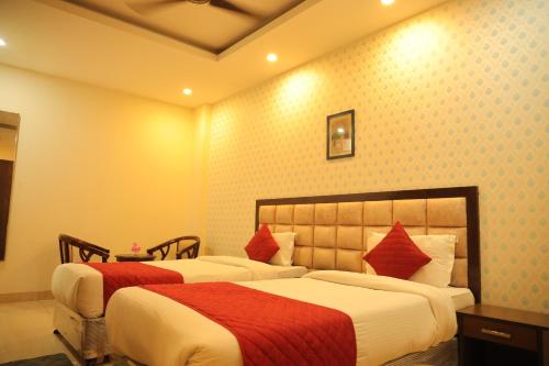 a hotel room with two beds with red pillows at Hotel Nirvana Suites in New Delhi