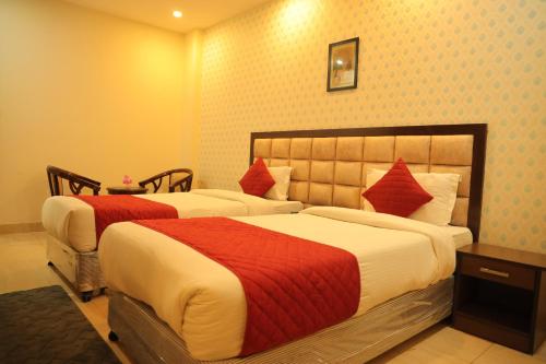 a bedroom with two beds with red and white sheets at Hotel Nirvana Suites in New Delhi