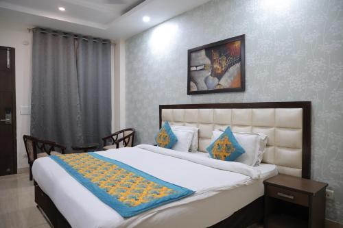 a bedroom with a large white bed with blue pillows at Hotel Nirvana Suites in New Delhi