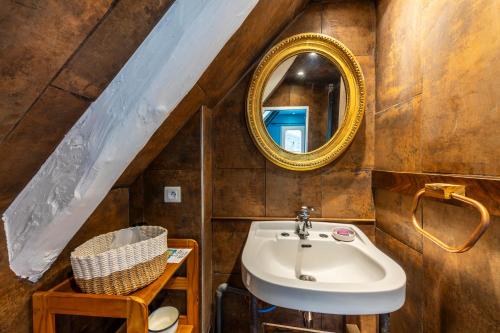 une salle de bain avec un lavabo et un miroir dans l'établissement Superbe chaumière en bord de mer, à Fouesnant
