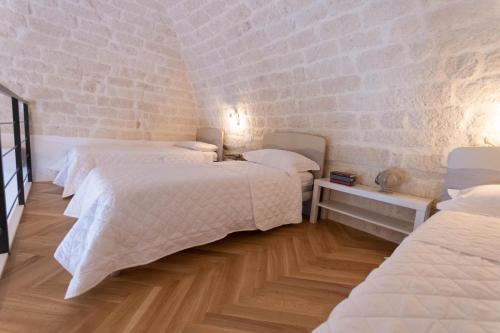 a bedroom with two beds and a brick wall at Centro Storico Rooms & Suites in Manfredonia