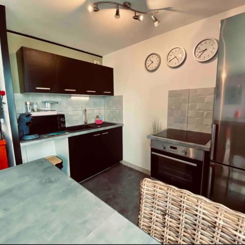 une cuisine avec 2 horloges sur le mur et un comptoir dans l'établissement Au Soleil Levant, à Calais