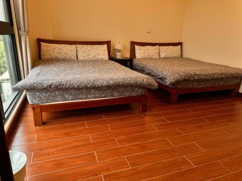 two beds in a room with a wooden floor at 舊事民宿 Old things in quemoy in Hu-hsia