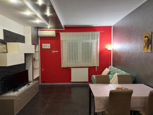 a room with a red wall and a table and chairs at Archimede's House in Ferrara