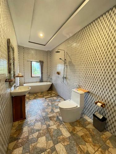 a bathroom with a tub and a toilet and a sink at Tirta Unda Sidemen in Sidemen