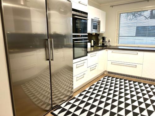 a kitchen with a refrigerator and a black and white checkered floor at Kaamos City House in Rovaniemi