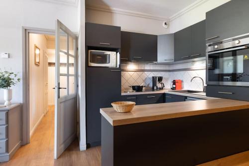a kitchen with black cabinets and a wooden counter top at Appartement 8 personnes dans chalet privé au pied des pistes in Val Thorens