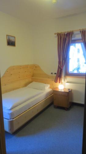 a bedroom with a wooden bed with a window and a bed sidx sidx sidx at Hotel Borest in Colfosco
