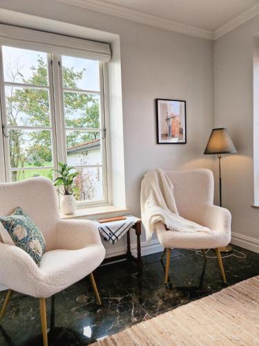 two chairs and a table in a room with two windows at Fontänens Bed & Breakfast in Trelleborg