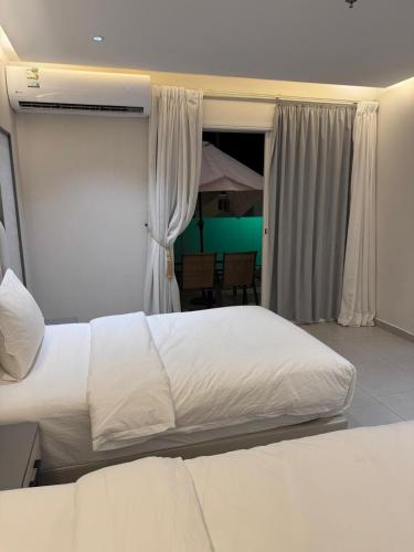 a bedroom with two white beds and a window at فندق حياة حقل الفندقية Hayat Haql Hotel in Al Humaizah