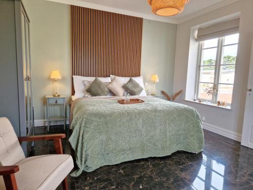 a bedroom with a bed with a green comforter and two windows at Fontänens Bed & Breakfast in Trelleborg