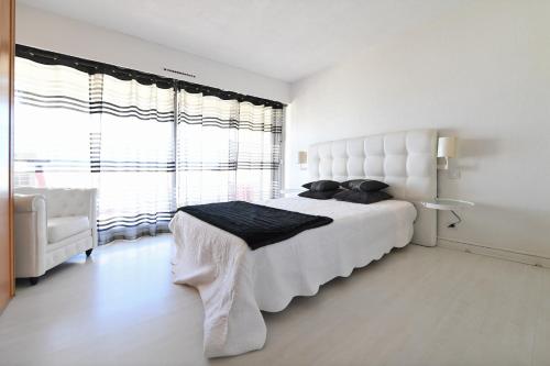 une chambre blanche avec un grand lit et une fenêtre dans l'établissement Appartement 1ère ligne Centre Ville calme vue mer - Accès direct à la plage, à La Grande Motte