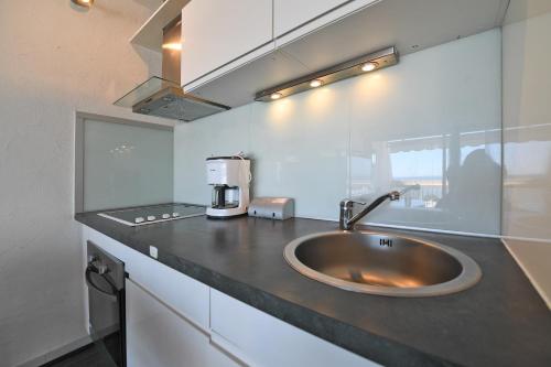 - une cuisine avec un évier et une cafetière sur un comptoir dans l'établissement Appartement 1ère ligne Centre Ville calme vue mer - Accès direct à la plage, à La Grande Motte