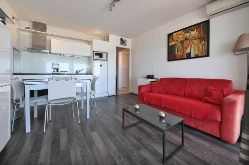 un salon avec un canapé rouge et une cuisine dans l'établissement Appartement 1ère ligne Centre Ville calme vue mer - Accès direct à la plage, à La Grande Motte