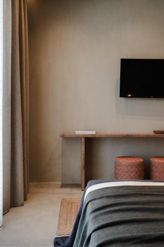 a bedroom with a bed and a tv on the wall at Tesoro Elegant escapes- suites in Naxos Chora