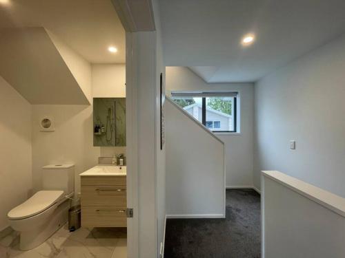 a bathroom with a toilet and a sink and a staircase at Parkside Retreat - 3 Beds -Sleeps 6 Near Westfield in Christchurch