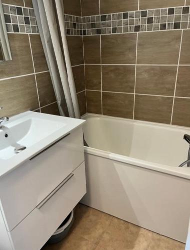 a bathroom with a white sink and a tub at Studio puy saint Vincent in Puy-Saint-Vincent