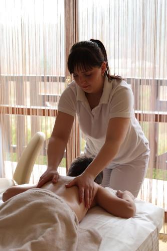 a woman sitting on a persons back while getting a massage at СПА-Готель "RESPECT" in Skhidnitsa