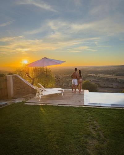 a man and a woman standing on a deck with an umbrella at Casa Alquerque in Monsaraz
