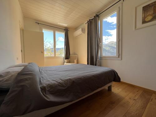 une chambre avec un grand lit et deux fenêtres dans l'établissement Les balcons de la Bollène-Vésubie, à La Bollène-Vésubie
