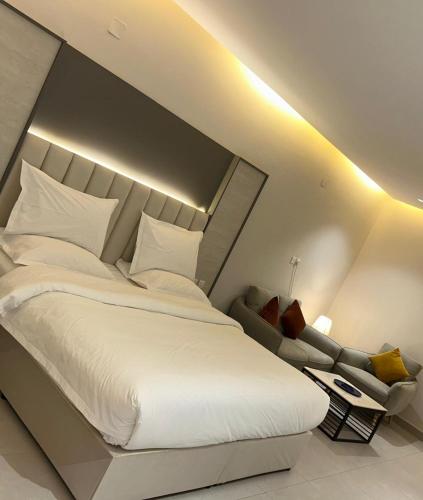 a bedroom with a large white bed and a couch at فندق حياة حقل الفندقية Hayat Haql Hotel in Al Humaizah