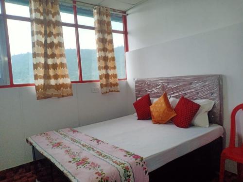 a bed in a room with two windows at Odyssey Stays Khirsu in Pauri