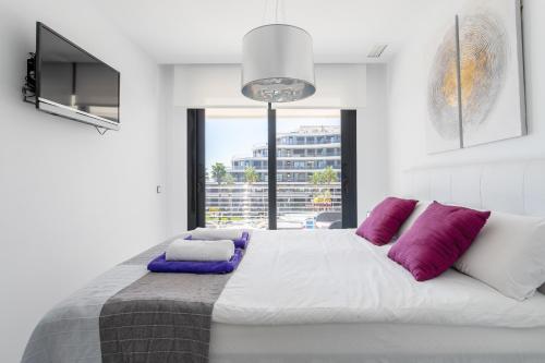 ein Schlafzimmer mit einem großen Bett mit lila Kissen in der Unterkunft Infinity View luxury beachfront apartment in Arenales del Sol