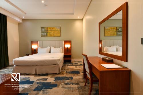 リヤドにあるRoof Hotel Apartmentsのベッドと机と鏡のある寝室