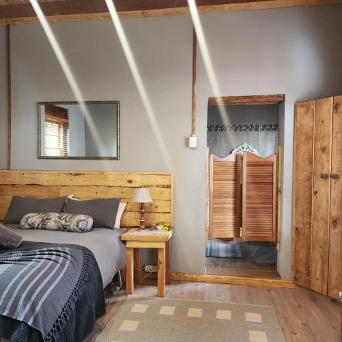 a bedroom with a bed and a table and a mirror at The Cottage in De Rust