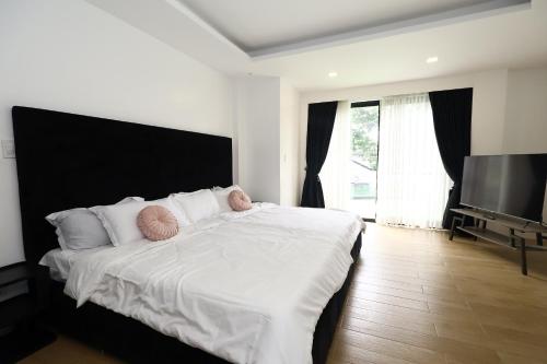 マニラにあるChez les Duques, BF Homes, Paranaqueの大きなベッドと薄型テレビのある寝室