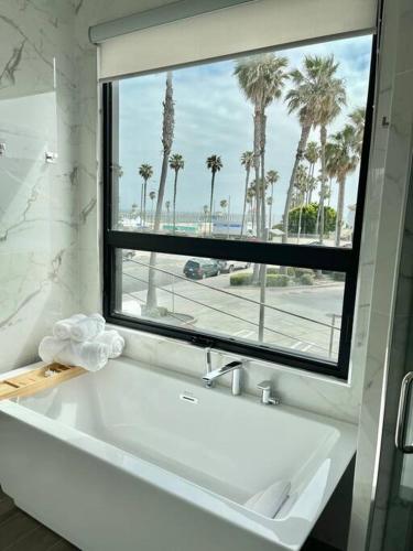 a bathroom with a large window and a white bath tub at Beach House with Rooftop Jacuzzi in Huntington Beach