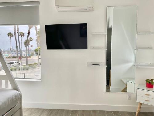 een woonkamer met een tv aan een witte muur bij Beach House with Rooftop Jacuzzi in Huntington Beach