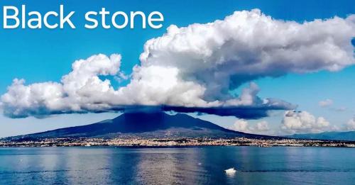 a cloud formation over a black stone island in the water at Black Stone in Pompei