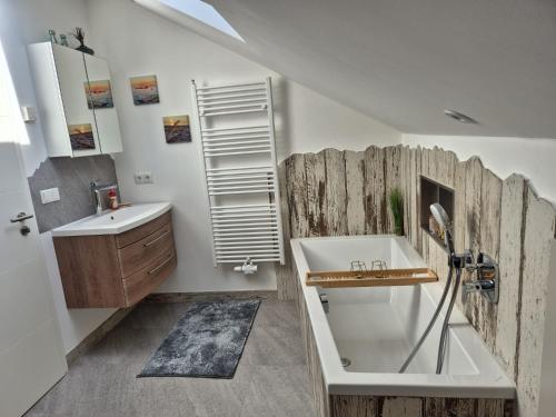 een badkamer met een witte wastafel en een houten muur bij Ferienwohnung Mariposa in Böbing