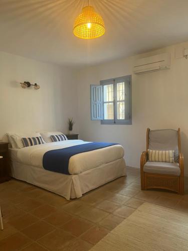 Casa del Patio في Pinos del Valle: غرفة نوم بها سرير كبير وكرسي