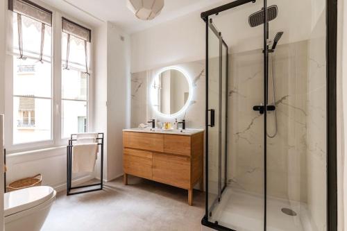 une salle de bain avec une douche, un lavabo et un miroir dans l'établissement Appartement moderne et calme, à Lyon