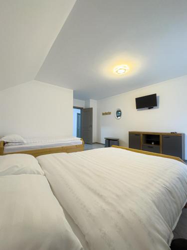 a bedroom with a large white bed and a flat screen tv at Casa Abrudan in Scrind-Frăsinet